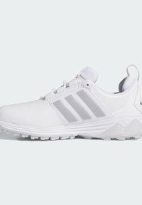 Baskets blanches de sport avec trois bandes grises sur le côté, semelle texturée et col rembourré sur un fond uni clair.