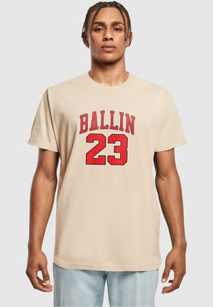 Bež majica iz bombaža s crvenim natpisom "BALLIN" iznad broja "23." Kratki rukavi i ležeran kroj.