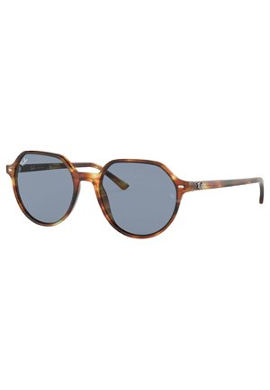 Occhiali da sole con montatura ottagonale in tartaruga, lenti a specchio grigie e aste sottili con logo. Design leggero e moderno.