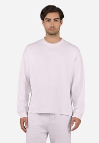 Light pink long-sleeve T-shirt made of soft cotton, featuring a crew neck and a relaxed fit, with subtle embossed branding on the chest.