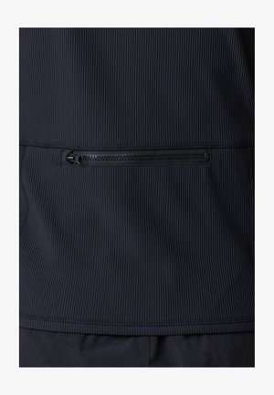 Navy zippered jacket with ridged texture, featuring a horizontal zip pocket on the back and flat seams at the hem and sides.