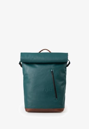 Tealfarbener Rucksack mit Rollverschluss, braunem Boden und Griff, diagonaler Reißverschlusstasche vorne und geprägtem "a/u" Logo auf glatter Lederoberfläche.