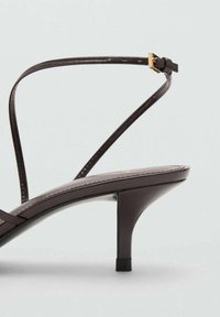 Bruna sandaler med remmar och en smal klack, med en slät läderfinish och en guldfärgad spänneaccent på anklaramen.