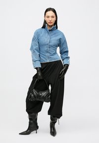 Denimjakk ülemise kraega, mustad nahkkindad, lahtised mustad püksid ja terava ninaga mustad kontsaga saapad. Must struktuurne käekott aktsentidega.