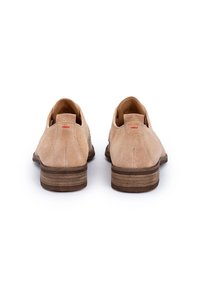 Lichte suède schoenen met een lage hak, een afgeronde neus en een klein rood accent op de hiel. Glad oppervlak en minimalistisch ontwerp.