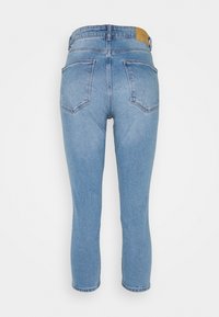 Jeans de denim azul claro con una cintura de altura media, cinco bolsillos y una etiqueta de cuero color marrón en la parte trasera. La tela tiene una textura suave.