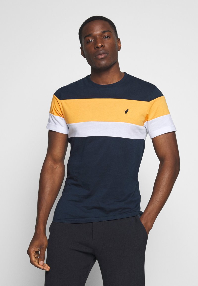 Short-sleeve T-shirt in navy, yellow, white, and gray stripes. Features a crew neck and a small logo on the chest. Made of cotton blend.