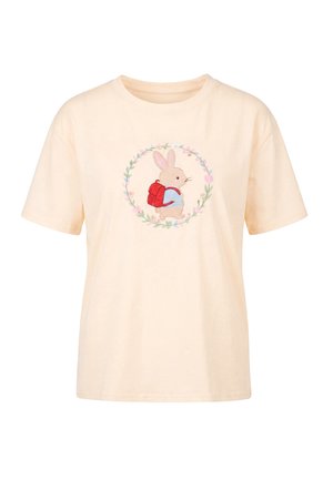 Beige T-shirt med en centreret tegneserie-kanin med rød rygsæk, omgivet af et blomsterkrans-design.