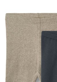 Kaksi paria legginssejä: yksi vaaleanbeige ribatulla pinnalla ja toinen tummanharmaa sileällä pinnalla, vierekkäin.