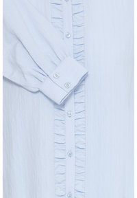 Chemise bleu clair à manches longues avec poignets boutonnés et détails de volants verticaux le long de la patte de boutonnage.