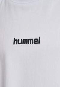 Hvid sportstrøje med en glat tekstur, med en sort "hummel"-logo tydeligt vist på brystet.