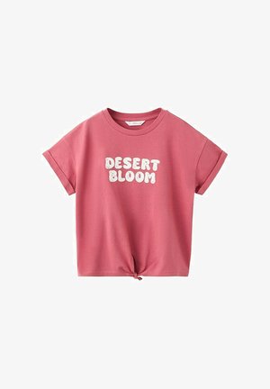 Ružové tričko s krátkym rukávom s otočenými manžetami, s uzlom na prednej strane a bielym textom "DESERT BLOOM" s textúrou na hrudi.