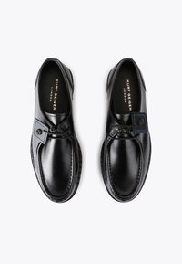 Zwarte leren schoenen met een gladde afwerking, ronde neus en blauw gestikte accenten. Voorzien van een decoratieve gestrikte overlay en een getextureerde zool.