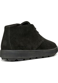 Botas de tobillo de ante negro con forma redondeada, un minimalismo en los cordones y una suela gruesa de goma con un patrón de relieve.