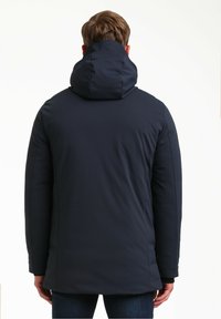 Chaqueta acolchada azul marino con cuello alto y capucha. Textura suave; diseñada con costuras mínimas y fabricada con tejido blando para mayor calidez.