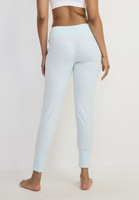Jasnoniebieskie dopasowane spodnie od piżamy z prążkowanymi mankietami na kostkach i miękkim, elastycznym pasem. Gładka tekstura materiału.