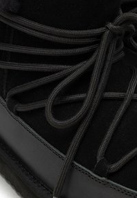 Czarny zamszowy but o teksturowanej powierzchni, sznurowadłach z siateczki i gumowej podeszwie. Posiada przeszywany akcent i zaokrąglony kształt noska.