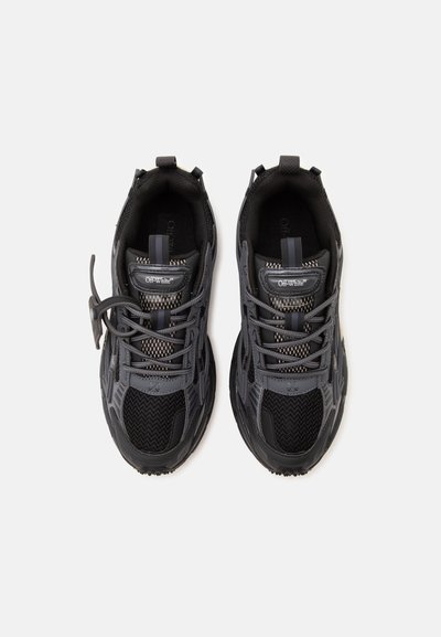 Ζευγάρι μαύρα και γκρι sneakers της μάρκας Off-White με λεπτομέρειες από δίχτυ και δέρμα, θέα από πάνω σε απλό ανοιχτό φόντο.