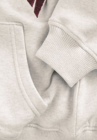 Hellgraues Sweatshirt mit geripptem Bündchen und Saum, einer vorderen Tasche und einem strukturierten bordeauxroten Akzent. Das Material wirkt weich und gemütlich.