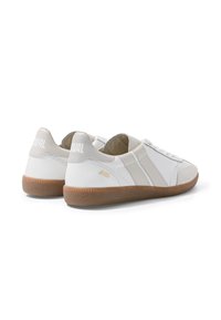 Paire de baskets blanches avec des accents beige, semelles en caoutchouc naturel et "JAVAL" imprimé sur la languette du talon, vues d’un angle arrière latéral.