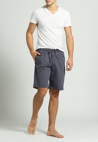 Donkergrijze gestreepte zwembroek met een elastische tailleband en een trekkoorddetail. Gecombineerd met een witte V-hals T-shirt.