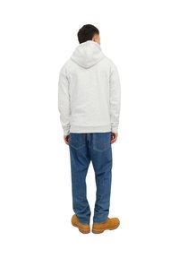 Grå hættetrøje med lange ærmer, der har en afslappet pasform, båret med blå denimjeans og brune støvler. Enkel design og blød tekstur.