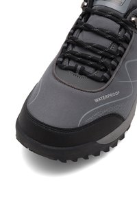 Gray waterproof hiking boot with black toe cap, textured sole, and black laces threaded through metal eyelets.