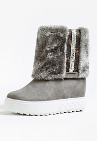 Botas de pelo sintético gris con un acabado de ante, que presentan un panel decorativo de rayas y una suela de plataforma blanca con detalles texturizados.
