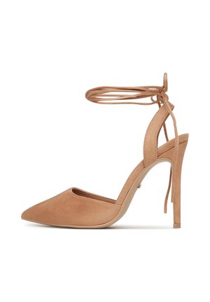 Nudefarbener Wildleder-Pumps mit spitzer Zehe und Knöchelriemen, ausgestattet mit einem eleganten Stiletto-Absatz und einer glatten Textur.