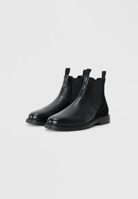 Black leather ankle boots with elastic side panels, rounded toe, and textured black suede accents. Sturdy black rubber sole.