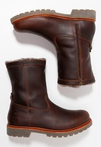 Bottines en cuir brun avec une finition texturée, dotées d'une fermeture éclair, d'une doublure douce et d'une semelle robuste avec des motifs de crampons prononcés.
