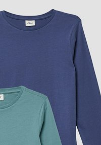 Twee katoenen t-shirts met lange mouwen: één in donkerblauw met een ronde hals, de ander in lichtgroen met een crew neck. Beide hebben een gladde textuur.