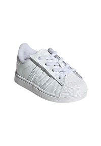 White sneaker with leather upper, textured toe, and lace-up closure. Features textured side stripes and a rubber outsole for grip.