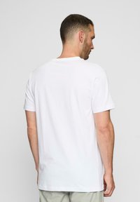 Hvid bomulds T-shirt, korte ærmer, rund hals, afslappet pasform, ensfarvet design, ingen synlige mønstre eller detaljer, set fra bagsiden.