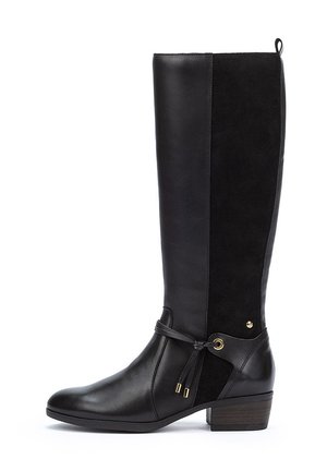 Bota negra hasta la rodilla que combina cuero liso y ante, con un tacón bajo y grueso, y acentos decorativos de cordones y herrajes.