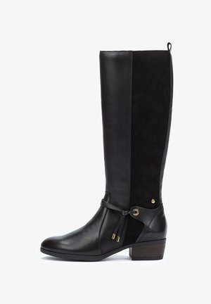 Bota negra hasta la rodilla que combina cuero liso y ante, con un tacón bajo y grueso, y acentos decorativos de cordones y herrajes.
