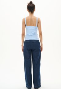 Débardeur côtelé bleu clair avec des fines bretelles associé à un jean large bleu foncé avec poches arrière et une légère évasement au bas.
