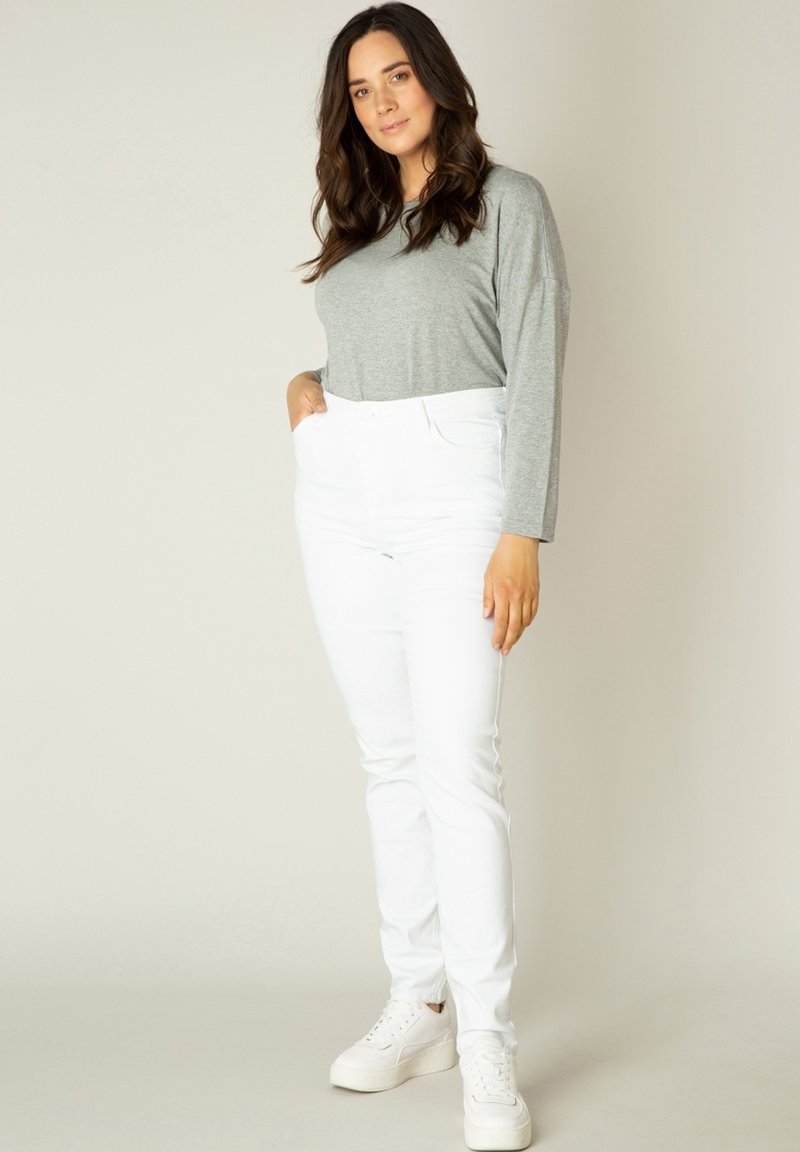 Grijze langemouwen top met een ronde hals, gecombineerd met hoge witte jeans en witte sneakers. Eenvoudig ontwerp, gladde textuur.