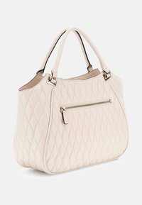 Borsa a tracolla trapuntata color crema con doppio manico e tasca con zip frontale, esposta su uno sfondo bianco.
