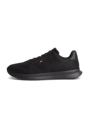 Sort let atletisk sneakers med mesh overdel, sort sål, snørebåndsdesign og lille rød, hvid og blå logo på siden.