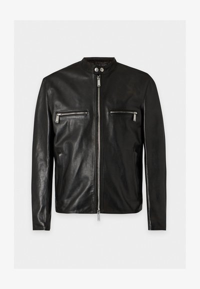 Veste en cuir noire avec fermeture éclair à l'avant, deux poches zippées horizontales sur la poitrine, col montant avec deux boutons-pression argentés et manches longues.