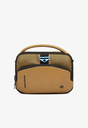 Compact tan- en bruine draagtas met zwarte rits, bovenhandvat en blauwe sluiting op het voorvak, gebrandmerkt met kleine zwarte logo's.
