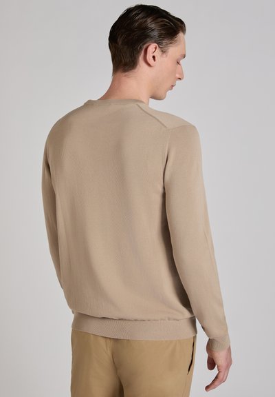 Suéter de punto beige con mangas largas, escote redondo y dobladillo acanalado. Textura lisa con costuras sutiles y sin patrones visibles.