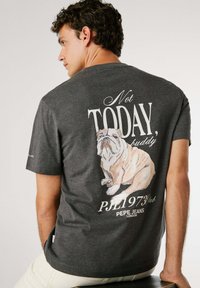 Donkergrijze t-shirt met een bulldogafbeelding op de achterkant. Bevat de tekst "Not TODAY, buddy" en het merkteken onder het ontwerp.