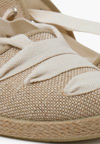 Beige espadrilky s tkaným textilním svrškem, krémovými šňůrkami a podrážkou obalenou jutou. Hladké akcenty a zaoblená špička.