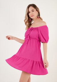 Felroze off-shoulder jurk met een aansluitend lijfje, pofmouwen, trekkoorddetails en een uitlopende, gelaagde rok. Structuurstof.