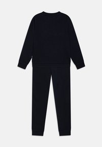Conjunto de sudadera y pantalones de chándal de algodón negro. Estilo de pullover con puños y dobladillo de canalé. Textura suave, corte relajado, sin patrones o logotipos visibles.