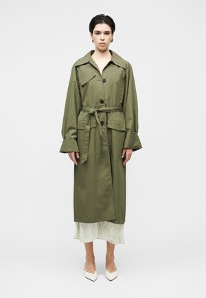 Φαρδιά παλτό τύπου τρεντς σε ελιά πράσινο με γιακά, μπροστινό μέρος με κουμπιά και ζώνη στη μέση. Διαθέτει μακριά μανίκια και ελαφρώς υφασμάτινη υφή.