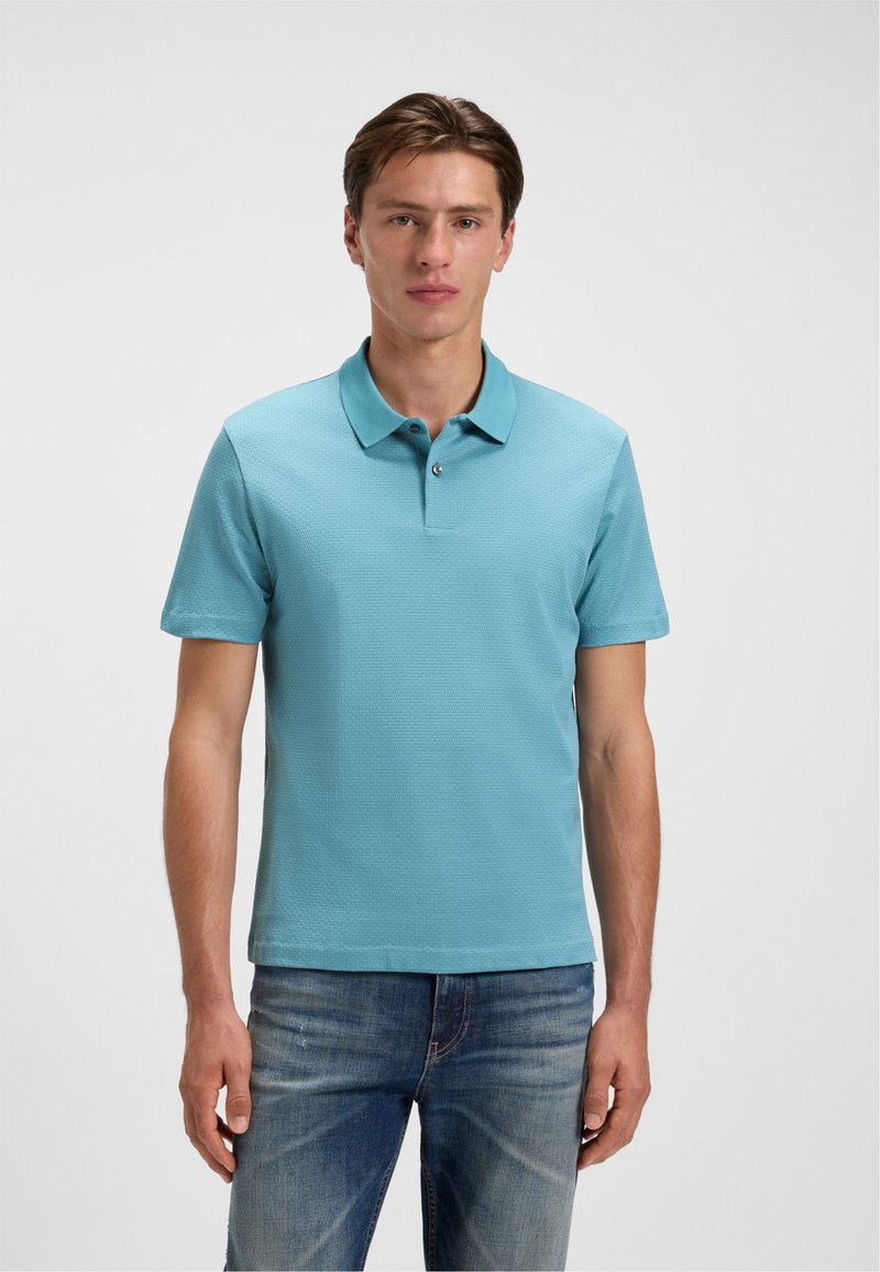 Lyseblå polo shirt lavet af tekstureret stof, med flad krave og korte ærmer. Kombineret med blå denim jeans.