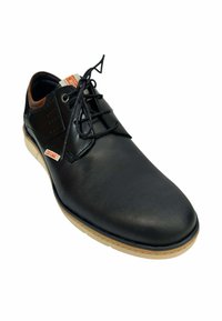 Zapato de cuero negro con un acabado suave, punta redonda y acentos en color marrón claro. Presenta un diseño con cordones y una suela de goma de color claro.